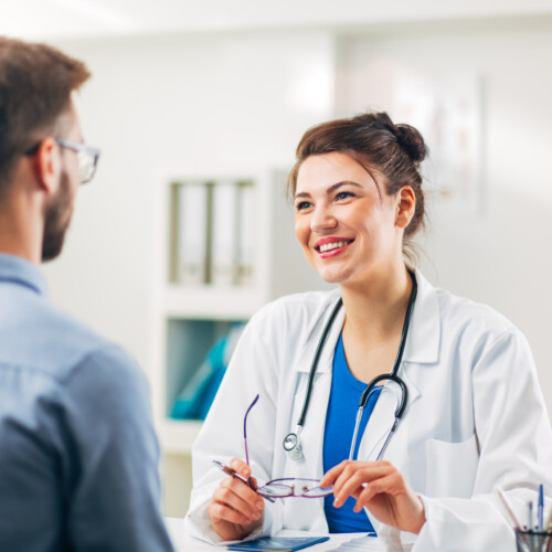 Woman Doctor talking to Patient at her Medical Office