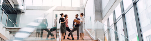 Group of young businesspeople standing on a staircase, talking.