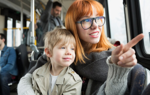 Mother and son pointing looking out bus window