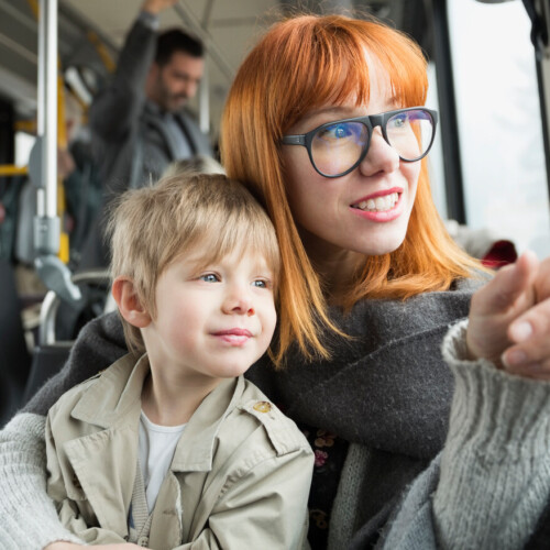 Mother and son pointing looking out bus window