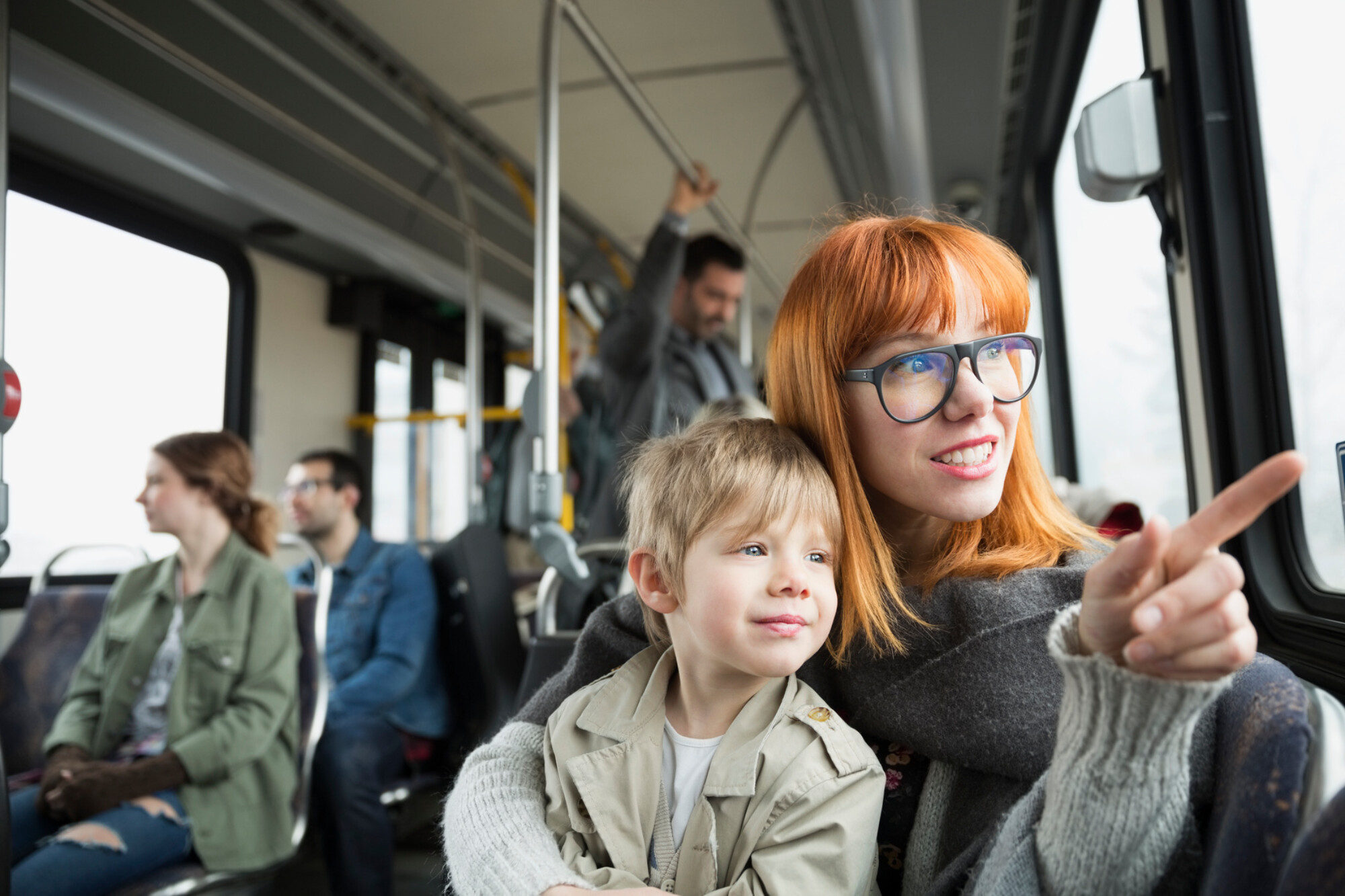 Mother and son pointing looking out bus window