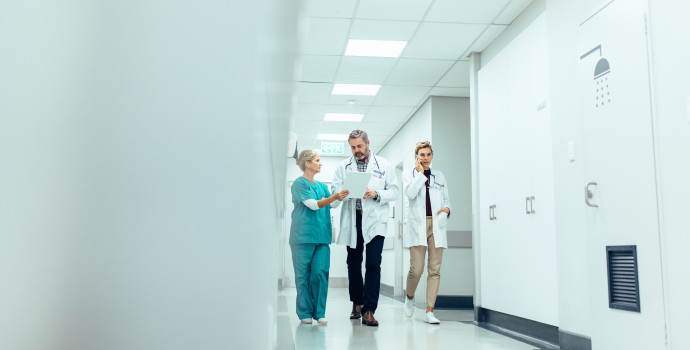 Group of medics with clipboard walking along hospital corridor