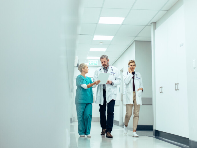 Group of medics with clipboard walking along hospital corridor