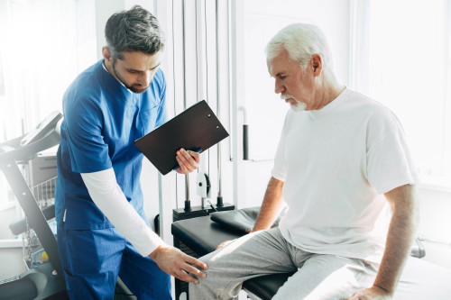 physiotherapist exam patient’s knee. Senior patient with knee injury visit his physiotherapist