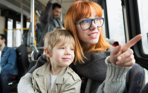 Mother and son pointing looking out bus window