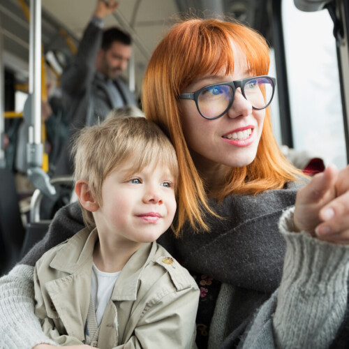 Mother and son pointing looking out bus window