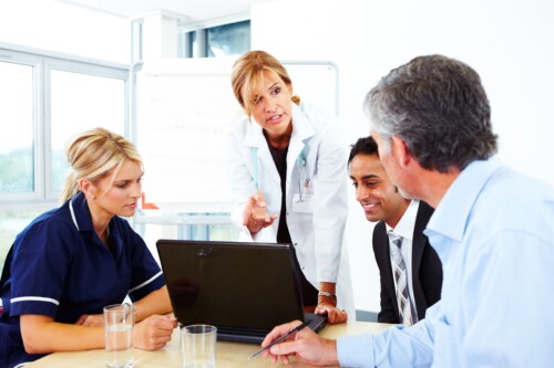 Female Doctor talking to businessmen and nurse in meeting