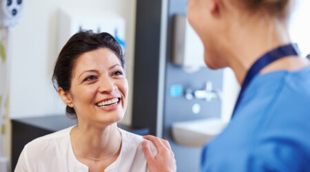 Female Patient Being Reassured By Doctor In Hospital Room