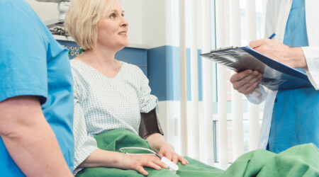 Doctor and nurse talking to patient in recovery room of hospital