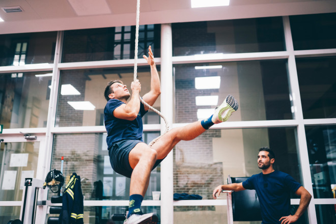 Fireman training hard at the station with a rope.