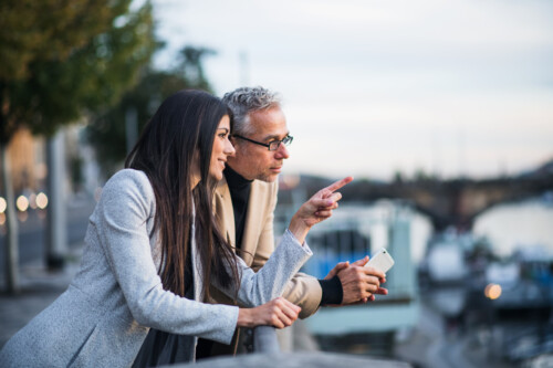 Man and woman business partners standing by a river in city of Prague.