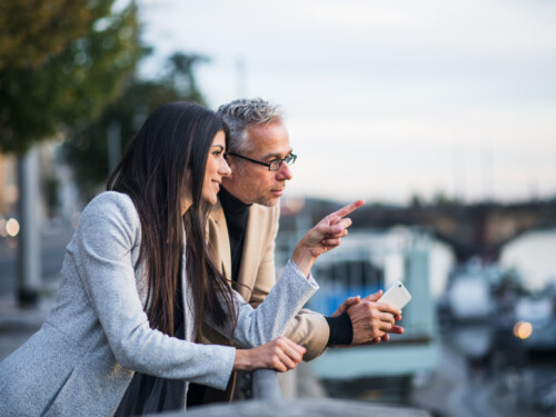 Man and woman business partners standing by a river in city of Prague.