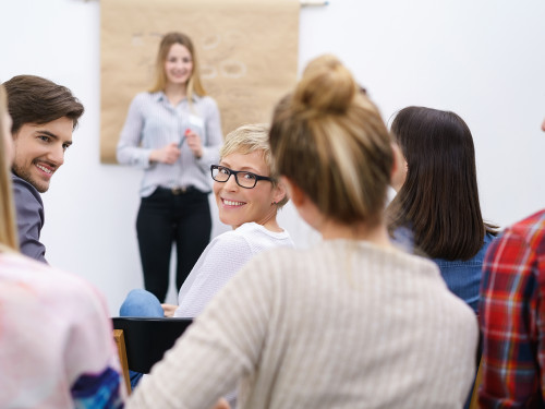 teilnehmer in einem vortrag schauen lächelnd über die schulter
