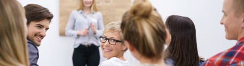 teilnehmer in einem vortrag schauen lächelnd über die schulter
