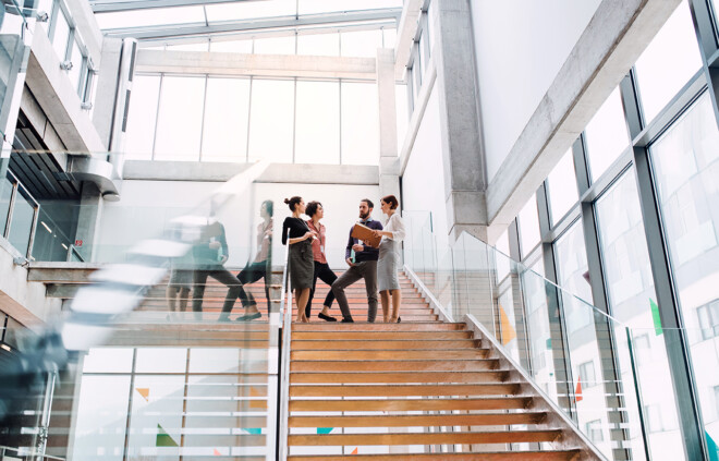 Group of young businesspeople standing on a staircase, talking.