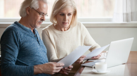 Serious worried senior couple reading documents calculating bill