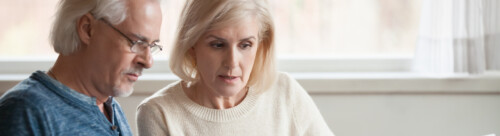 Serious worried senior couple reading documents calculating bill