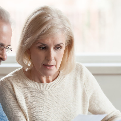 Serious worried senior couple reading documents calculating bill