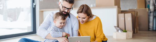 A young family with a toddler girl moving in new home, using tablet.