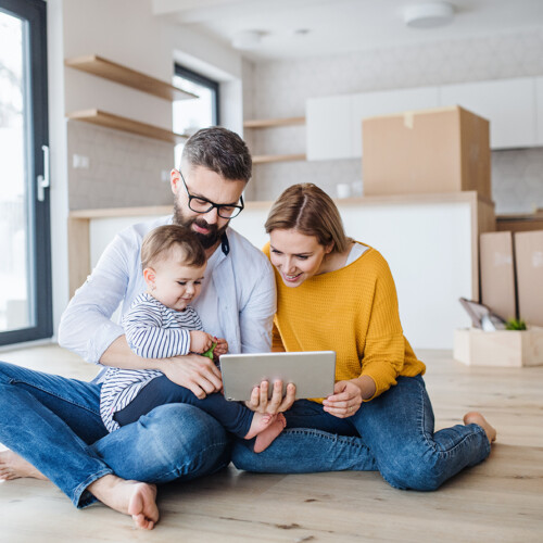 A young family with a toddler girl moving in new home, using tablet.