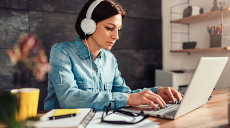 Woman using laptop and listening music on a headphones