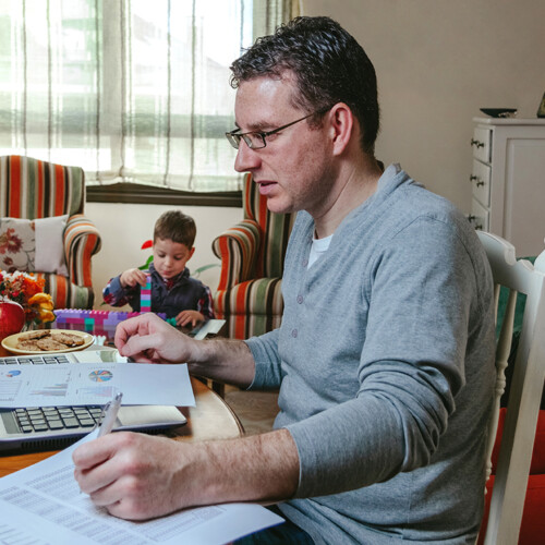 Father working at home while her son plays