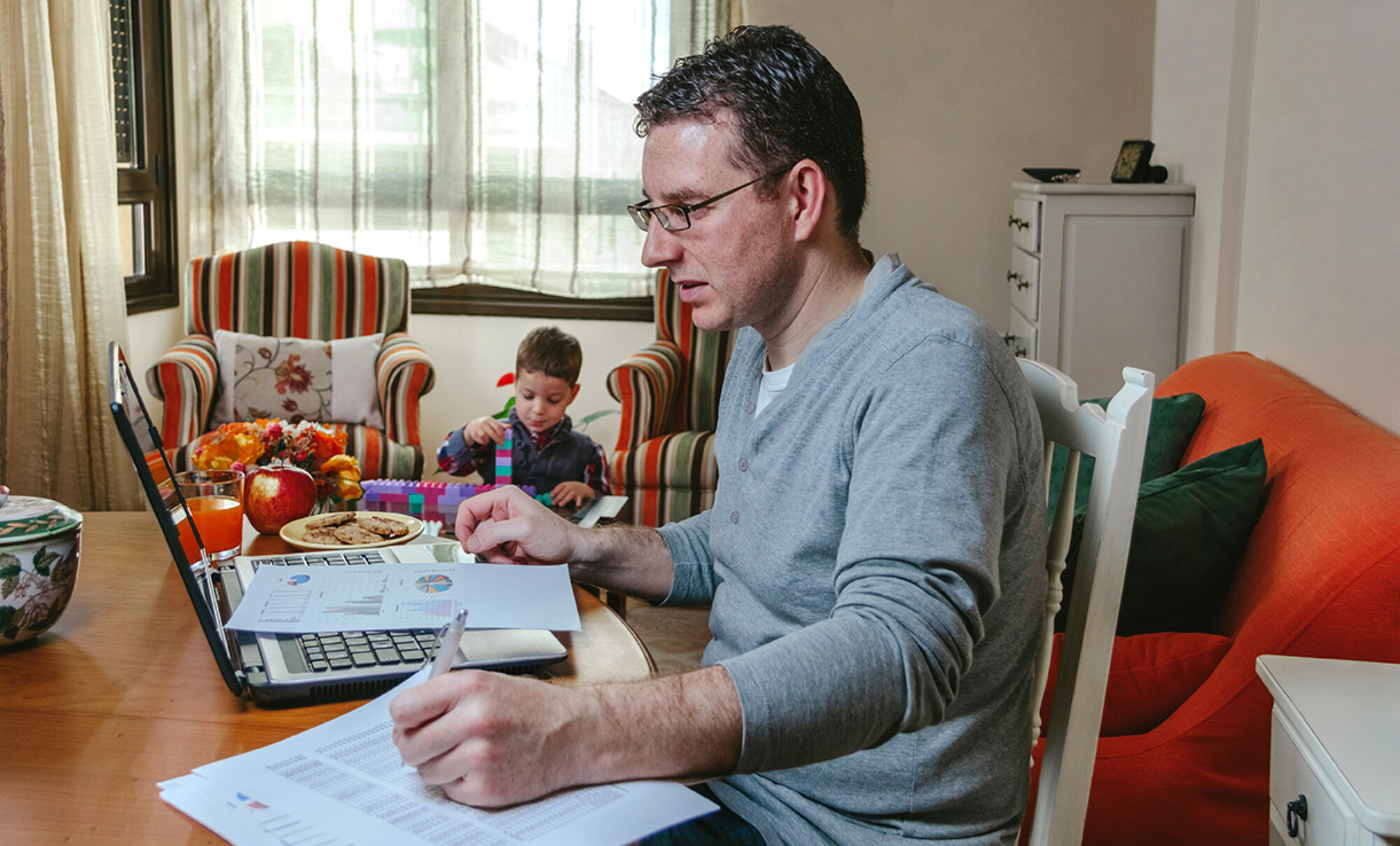 Father working at home while her son plays