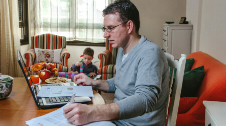 Father working at home while her son plays