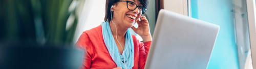 Sixty year old female teacher wearing headphones having online c