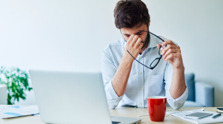 Young businessman having headache while working in home office