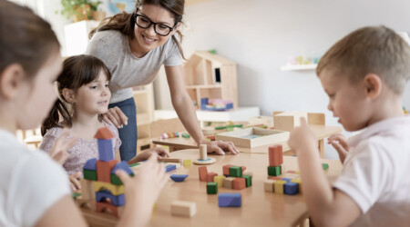 Preschool teacher with children playing with colorful wooden did