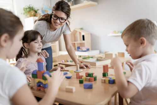 Preschool teacher with children playing with colorful wooden did