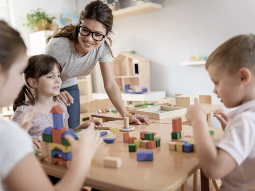 Preschool teacher with children playing with colorful wooden did