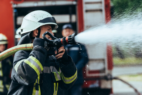 selective focus of firefighter with water hose extinguishing fir