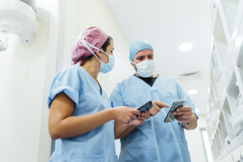 Doctors using cell phones in the hospital corridor. Medical concept