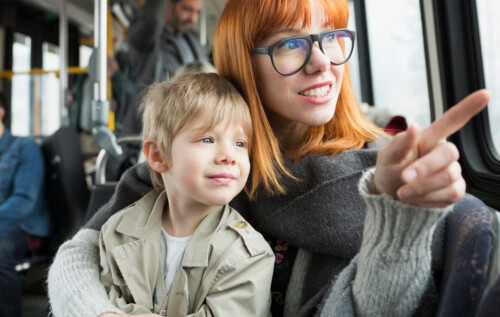Mother and son pointing looking out bus window