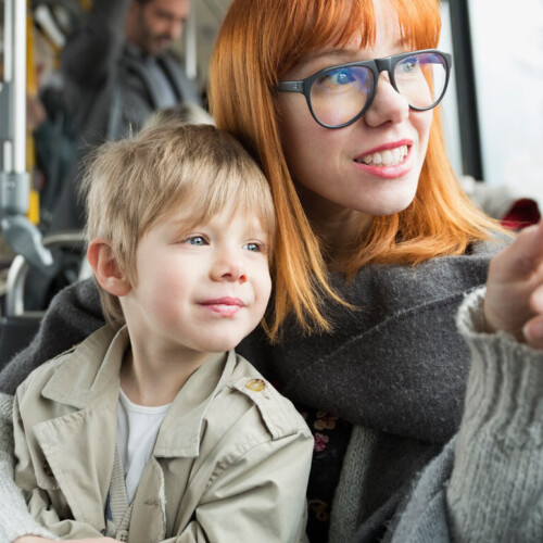 Mother and son pointing looking out bus window