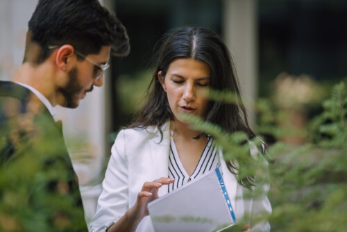 Businessman and businesswoman checking documents in the street