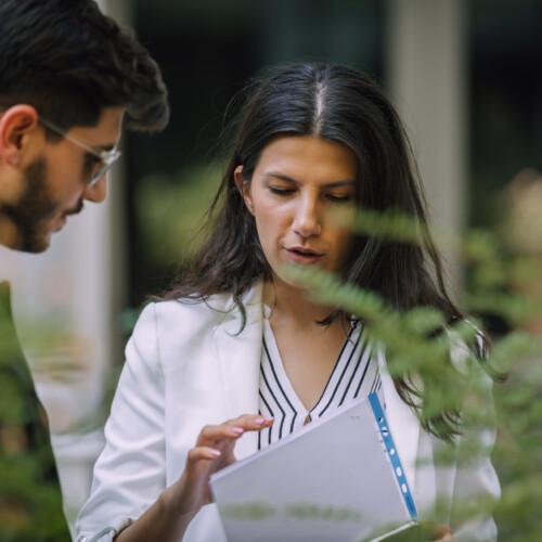 Businessman and businesswoman checking documents in the street