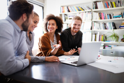 Working together on project. Happy young business colleagues working in office