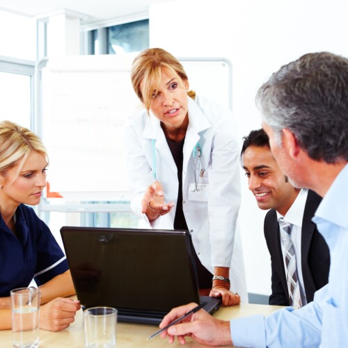 Female Doctor talking to businessmen and nurse in meeting
