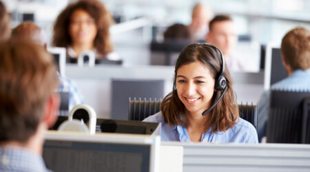 Young woman working in call centre, surrounded by colleagues