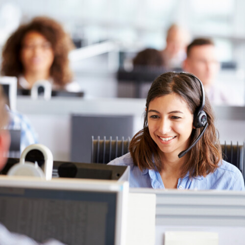 Young woman working in call centre, surrounded by colleagues