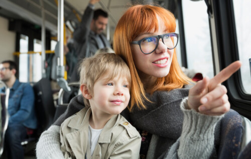 Mother and son pointing looking out bus window