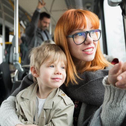 Mother and son pointing looking out bus window