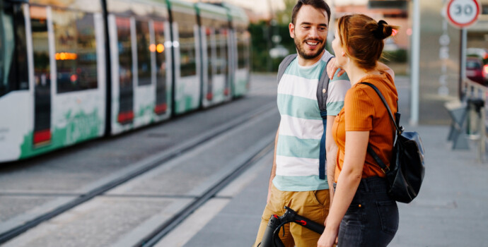 Couple with folded electric scooter waiting at tram stop