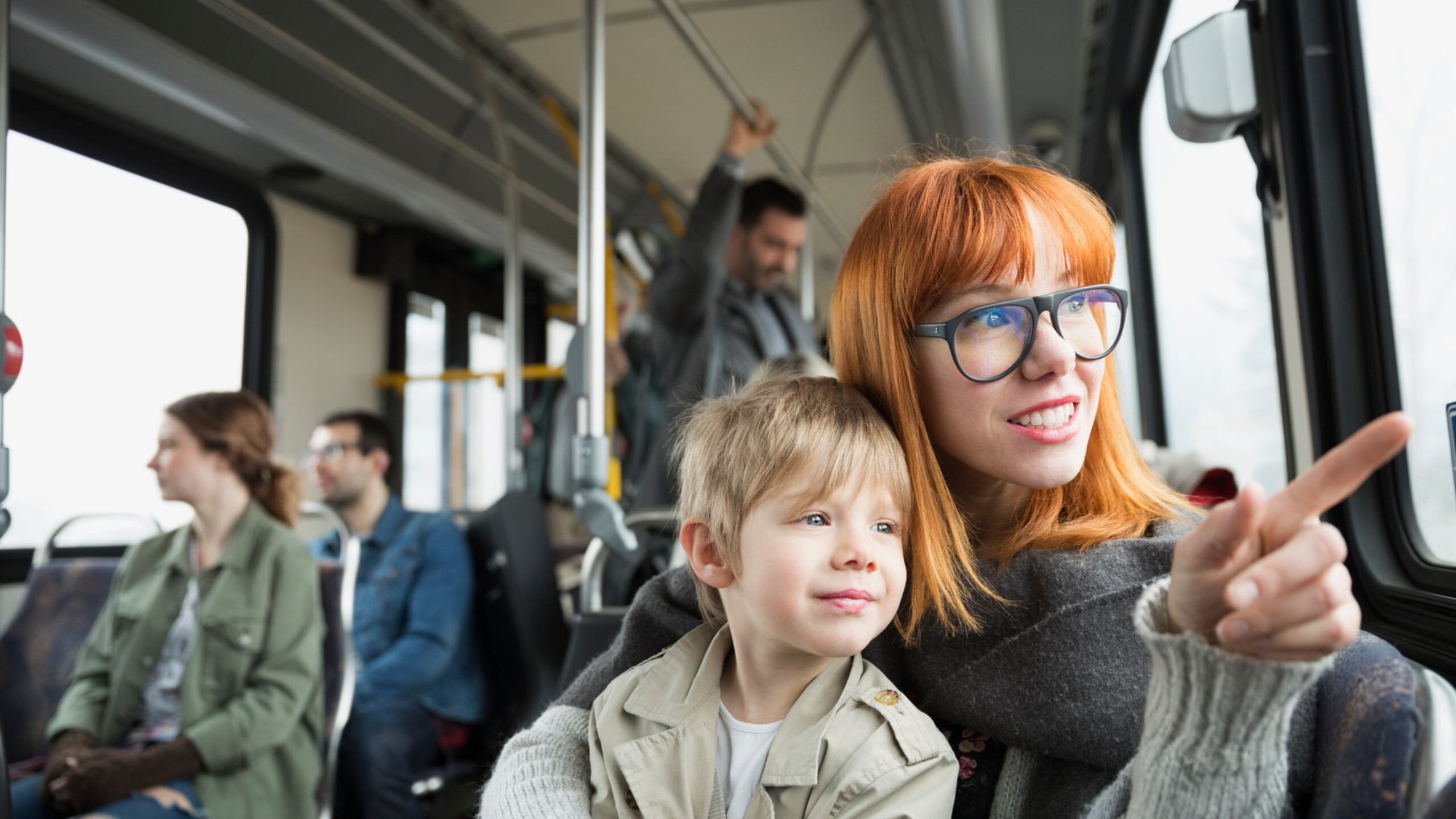 Mother and son pointing looking out bus window