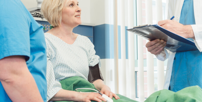 Doctor and nurse talking to patient in recovery room of hospital