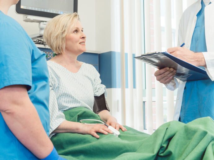 Doctor and nurse talking to patient in recovery room of hospital