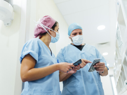 Doctors using cell phones in the hospital corridor. Medical concept